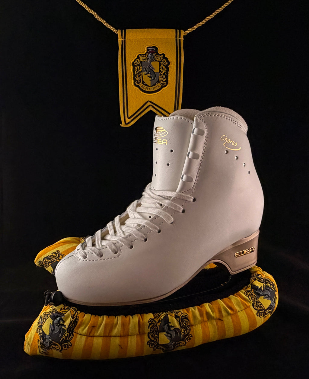 Yellow and black wizard house inspired blade soakers shown on a figure skate